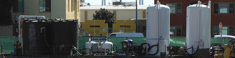 A wide view of Pure Effect black tanks, white carbon vessels and a green frac tank staged at a jobsite