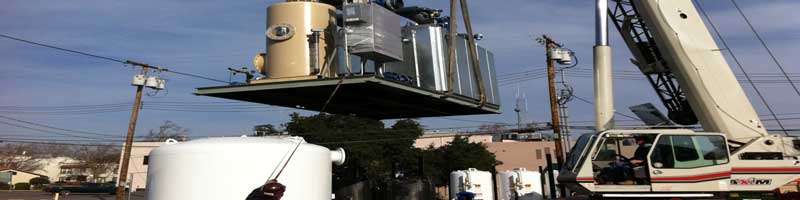 A mobile crane lifting a Pure Effect air-treatment unit over carbon vessels at the Pure Effect equipment yard