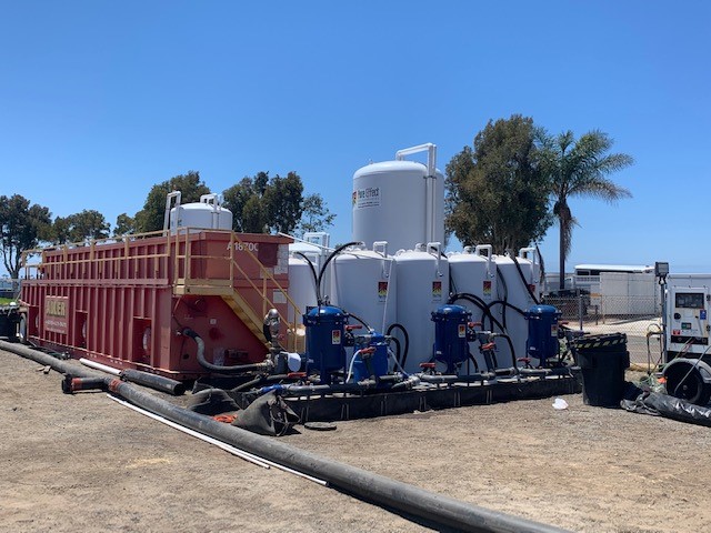A blue frac tank and a long row of white and blue Pure Effect treatment tanks at a large graded dewatering jobsite
