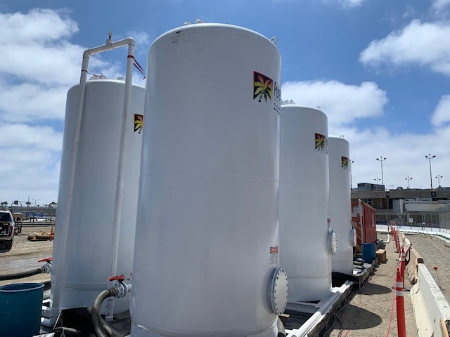 Several white Pure Effect carbon vessels lined up against a partly cloudy sky at a jobsite