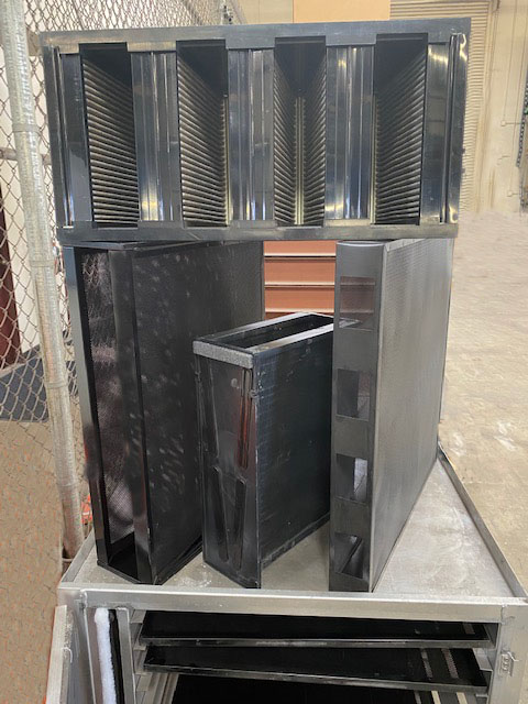 A set of black carbon filter media panels and blocks staged on a metal cart indoors