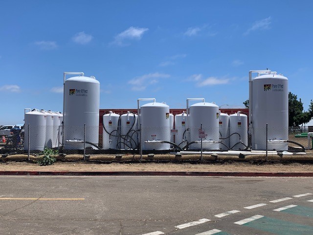 A red Pure Effect frac tank paired with white carbon vessels and blue bag filters at a San Diego dewatering jobsite