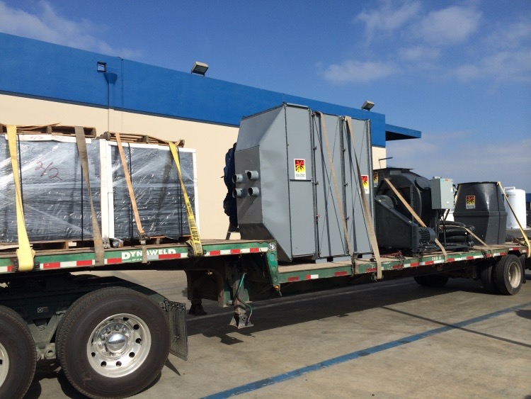 A gray Pure Effect carbon air-treatment unit strapped to a flatbed truck for delivery